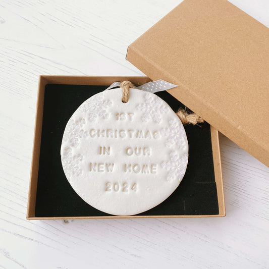 Personalised first Christmas in our new home bauble ornament, pearlised white round clay with 1ST CHRISTMAS IN OUR NEW HOME 2024 (text not painted), decorated with 3 iridescent glitter snowflakes on either side of the bauble