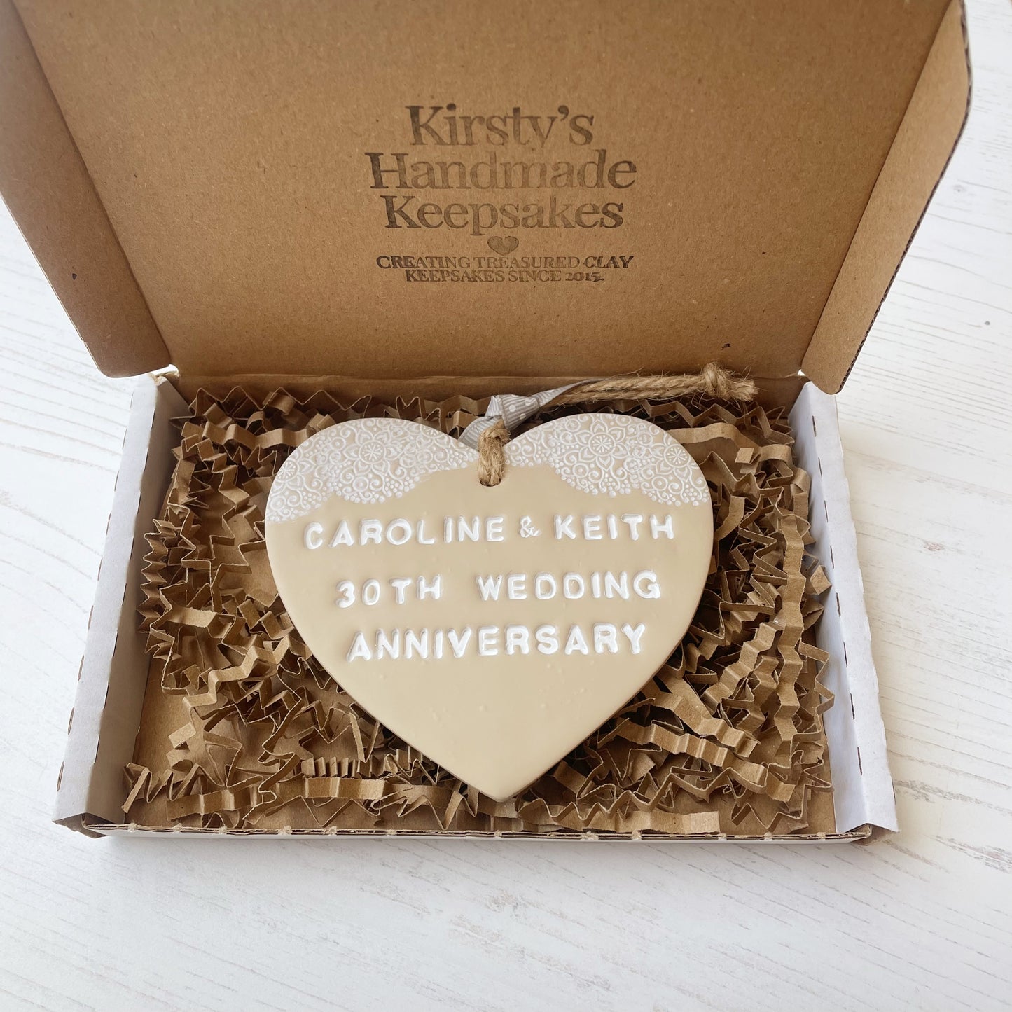 Personalised anniversary gift, beige clay heart with a white lace edge at the top of the heart with jute twine for hanging, the heart is personalised with CAROLINE & KEITH 30TH WEDDING ANNIVERSARY