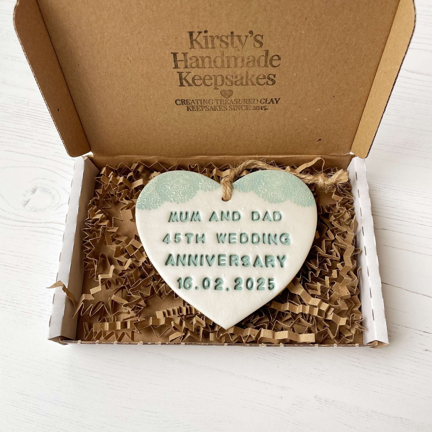 Personalised 45th anniversary gift, pearlised white clay hanging heart with a sage green lace edge at the top of the heart, the heart is personalised with MUM AND DAD 45TH WEDDING ANNIVERSARY 16.02.2025