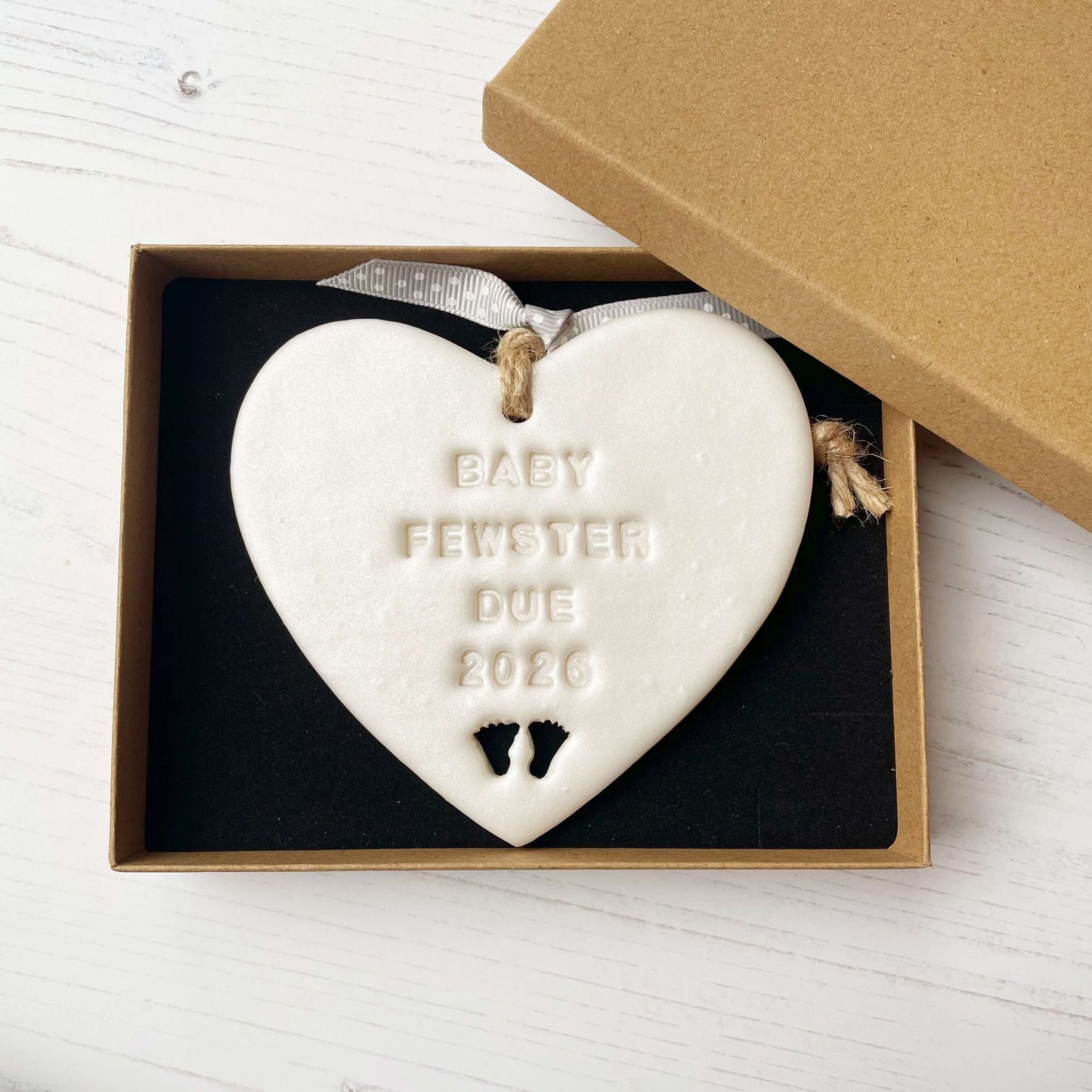 Personalised baby reveal gift, pearlised white clay heart with feet cut out of the bottom personalised with BABY FEWSTER DUE 2026