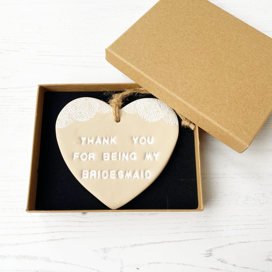 Personalised Bridesmaid thank you gift, beige clay hanging heart with a white lace edge at the top of the heart, the heart is personalised with THANK YOU FOR BEING MY BRIDESMAID In a luxury Kraft brown gift box