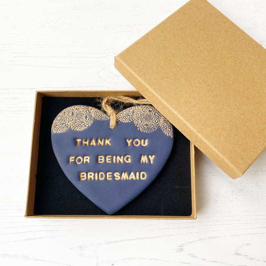 Personalised Bridesmaid thank you gift, navy clay hanging heart with a gold lace edge at the top of the heart, the heart is personalised with THANK YOU FOR BEING MY BRIDESMAID In a luxury Kraft brown gift box