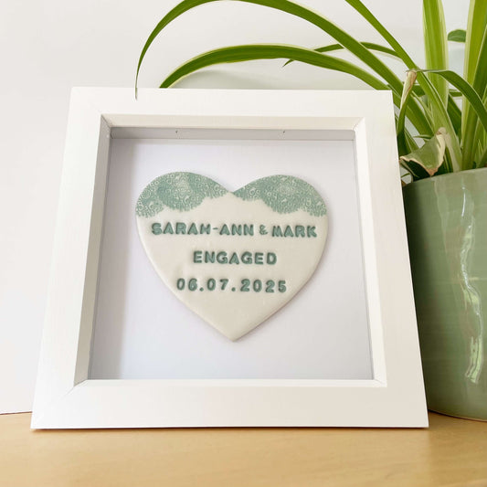 Personalised framed engagement gift, pearlised white clay heart with a white lace edge at the top of the heart in a white box frame, the heart is personalised with SARAH-ANN & MARK ENGAGED 06.07.2025