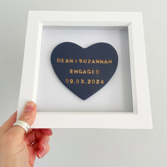 Personalised framed engagement gift, dark blue clay heart personalised in gold with DEAN & SUZANNAH ENGAGED 09.03.2024