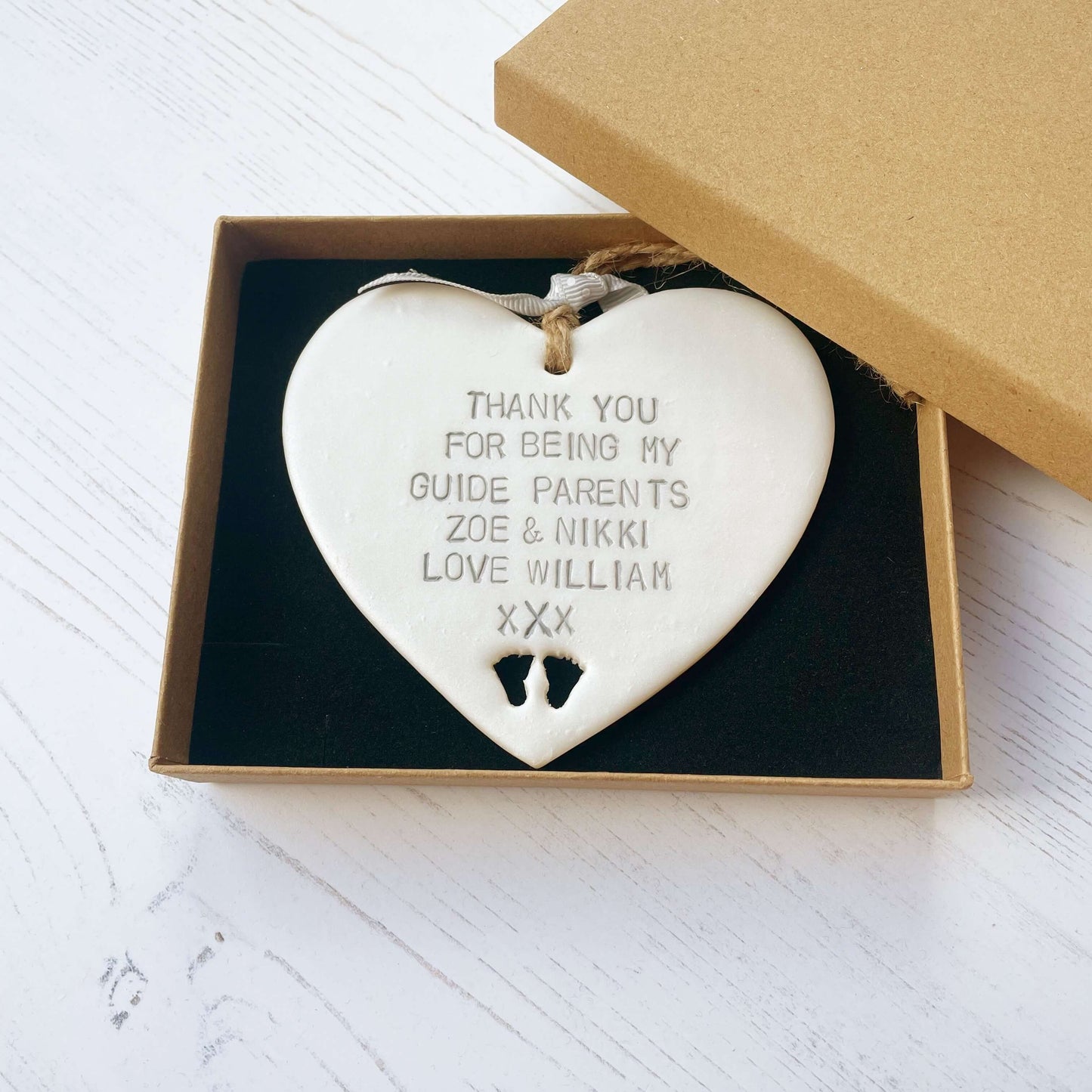 Personalised guide parents gift, pearlised white clay hanging heart with baby feet cut out of the bottom, the heart is personalised with THANK YOU FOR BEING MY GUIDE PARENTS ZOE & NIKKI LOVE WILLIAM xXx In a brown Kraft luxury gift box