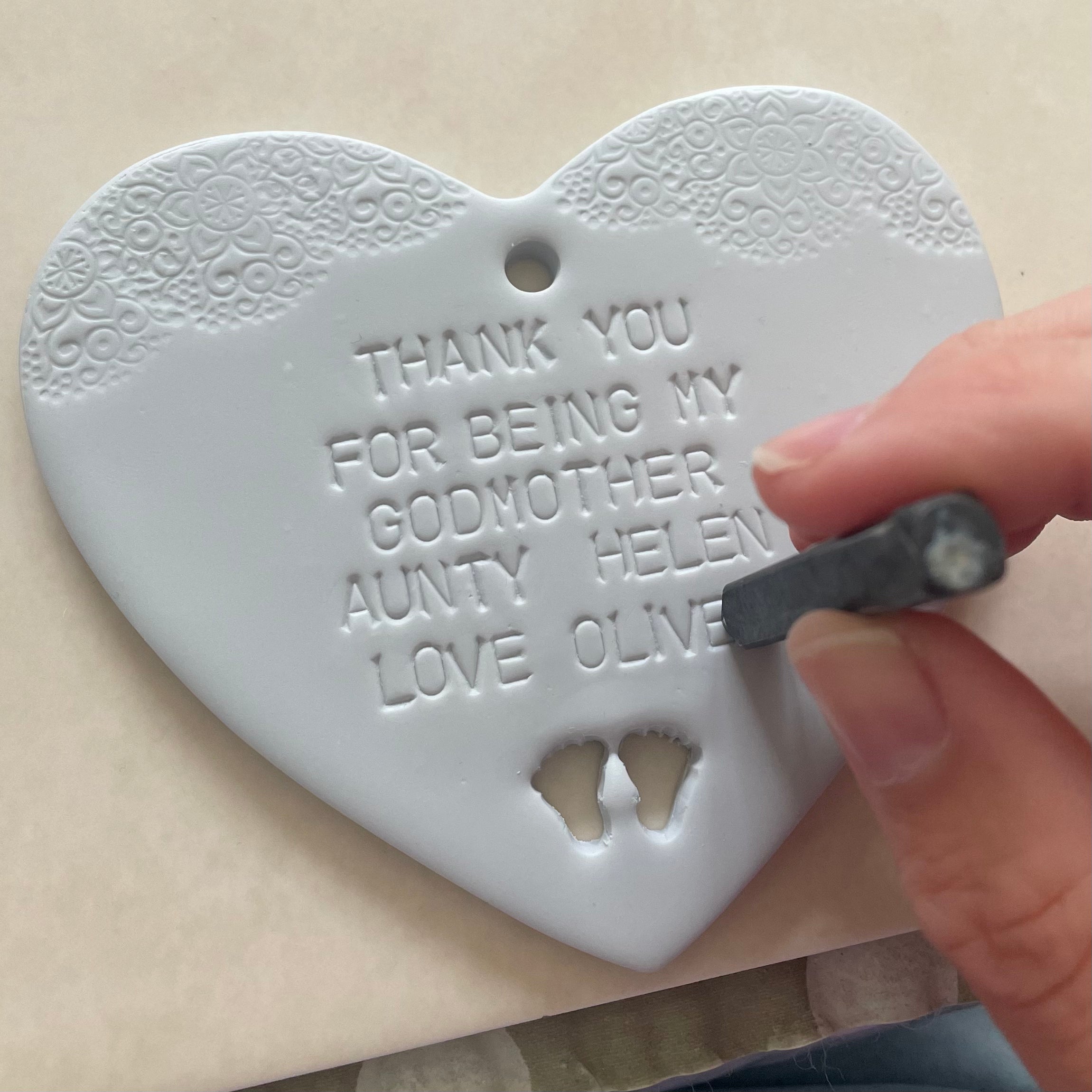Kirsty hand stamping the personalisation onto the grey Godmother heart