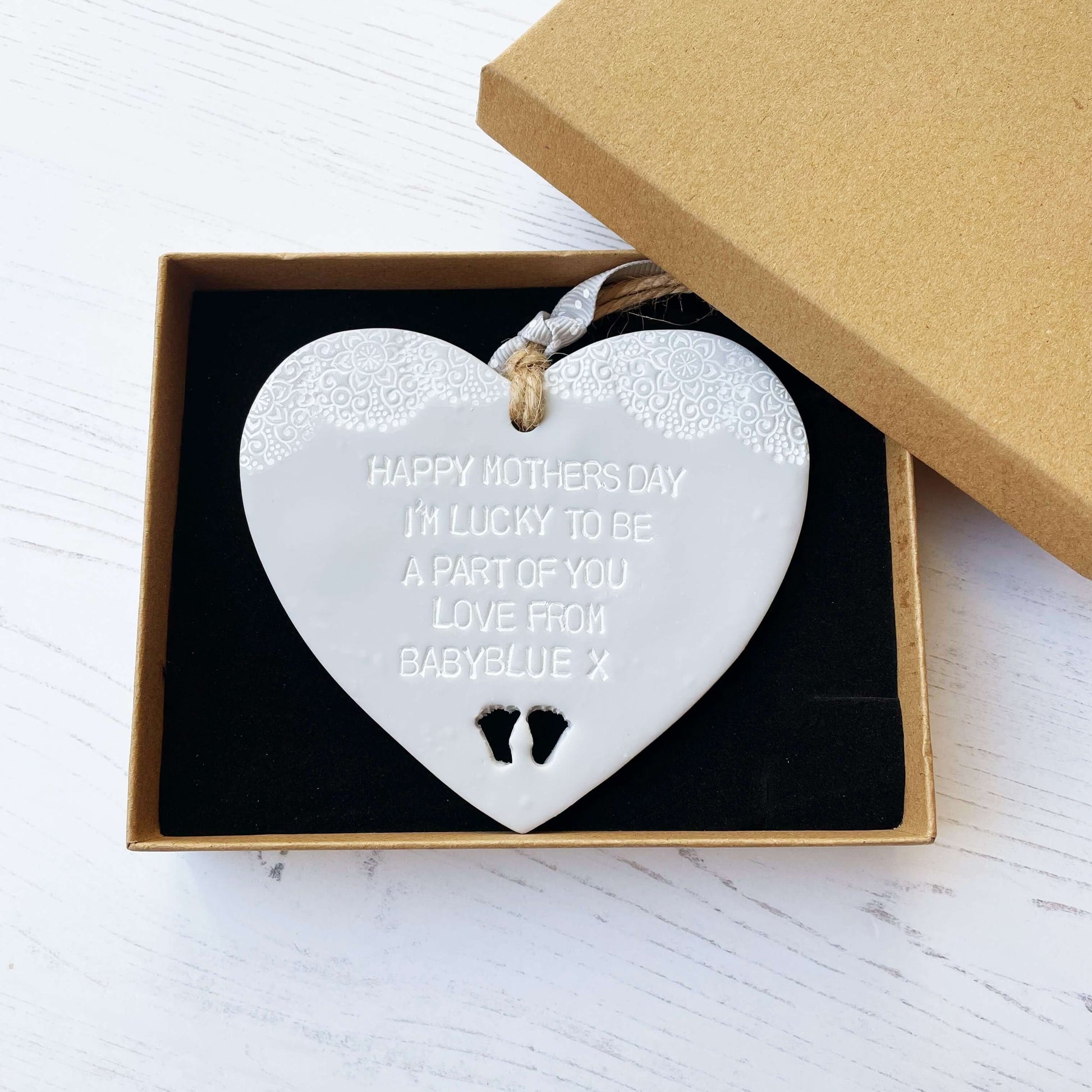 Personalised first Mother’s Day gift, grey clay hanging heart with baby feet cut out at the bottom of the heart and a white lace edge at the top of the heart, the heart is personalised with HAPPY MOTHER’S DAY I’M LUCKY TO BE A PART OF YOU LOVE FROM BABYBLUE X
