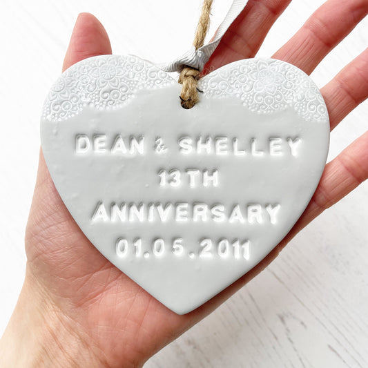 Personalised anniversary gift, grey clay heart with a white lace edge at the top of the heart with jute twine for hanging, the heart is personalised with DEAN & SHELLEY 13TH ANNIVERSARY 01.05.2011