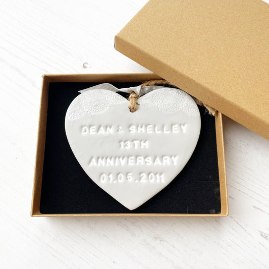 Personalised anniversary gift, grey clay heart with a white lace edge at the top of the heart with jute twine for hanging, the heart is personalised with DEAN & SHELLEY 13TH ANNIVERSARY 01.05.2011 In a brown Kraft luxury gift box