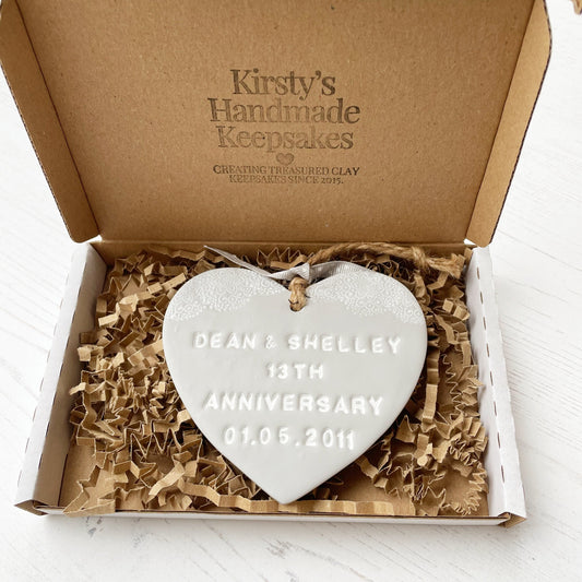 Personalised anniversary gift, grey clay heart with a white lace edge at the top of the heart with jute twine for hanging, the heart is personalised with DEAN & SHELLEY 13TH ANNIVERSARY 01.05.2011 In a postal box with brown Kraft shredded zigzag paper
