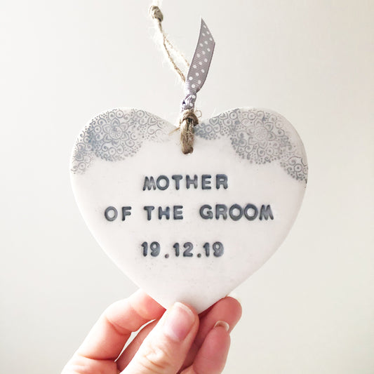 Personalised Bridesmaid thank you gift, pearlised white clay hanging heart with a grey lace edge at the top of the heart, the heart is personalised with MOTHER OF THE GROOM 19.12.19