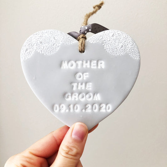 Personalised Bridesmaid thank you gift, grey clay hanging heart with a white lace edge at the top of the heart, the heart is personalised with MOTHER OF THE GROOM 09.10.2020