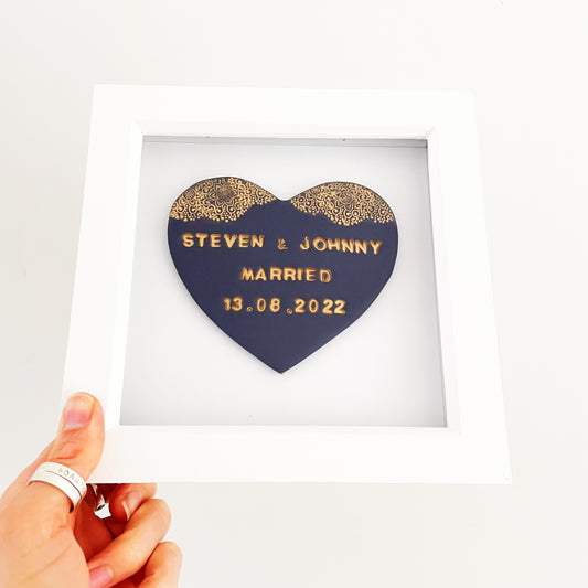 Personalised framed wedding gift, navy clay heart with a gold lace edge at the top of the heart in a white box frame, the heart is personalised with STEVEN & JOHNNY MARRIED 13.08.2022