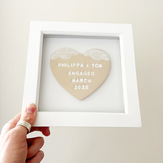 Personalised framed engagement gift, beige clay heart with a white lace edge at the top of the heart in a white box frame, the heart is personalised with PHILIPPA & TOM ENGAGED MARCH 2022