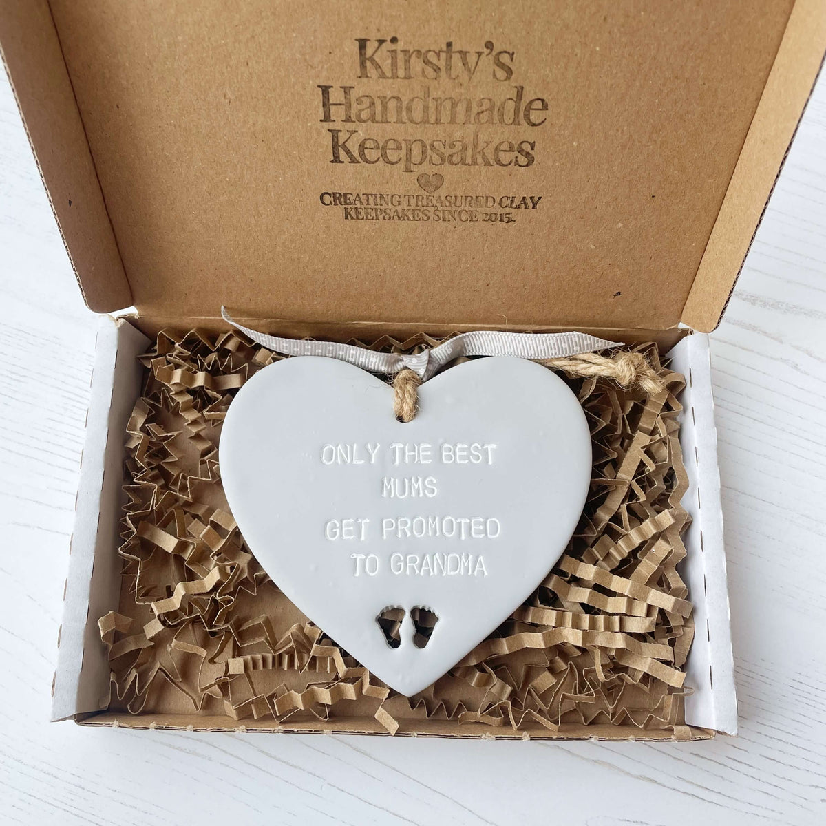 Grey clay hanging heart with baby feet cut out of the bottom and white personalisation, the heart is personalised with ONLY THE BEST MUMS GET PROMOTED TO GRANDMA