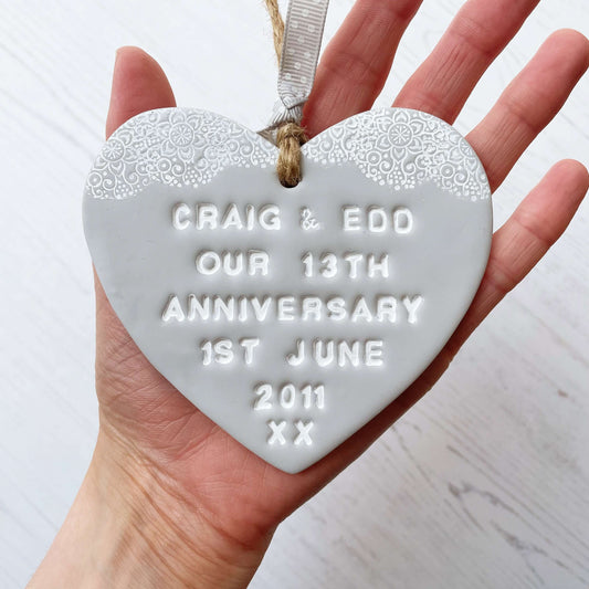 Personalised anniversary gift, grey clay heart with a white lace edge at the top of the heart with jute twine for hanging, the heart is personalised with CRAIG & EDD OUR 13TH ANNIVERSARY 1ST JUNE 2011 XX