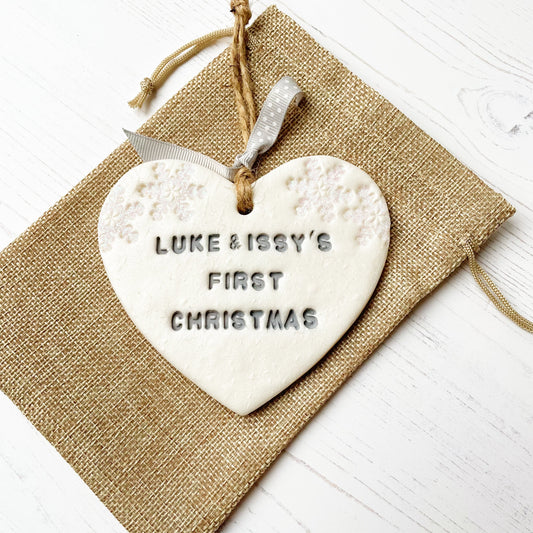 Personalised our first Christmas together heart ornament, pearlised white clay with LUKE & ISSY'S FIRST CHRISTMAS 2020 painted grey, decorated with 2 iridescent glitter snowflakes on either side of the top of the heart