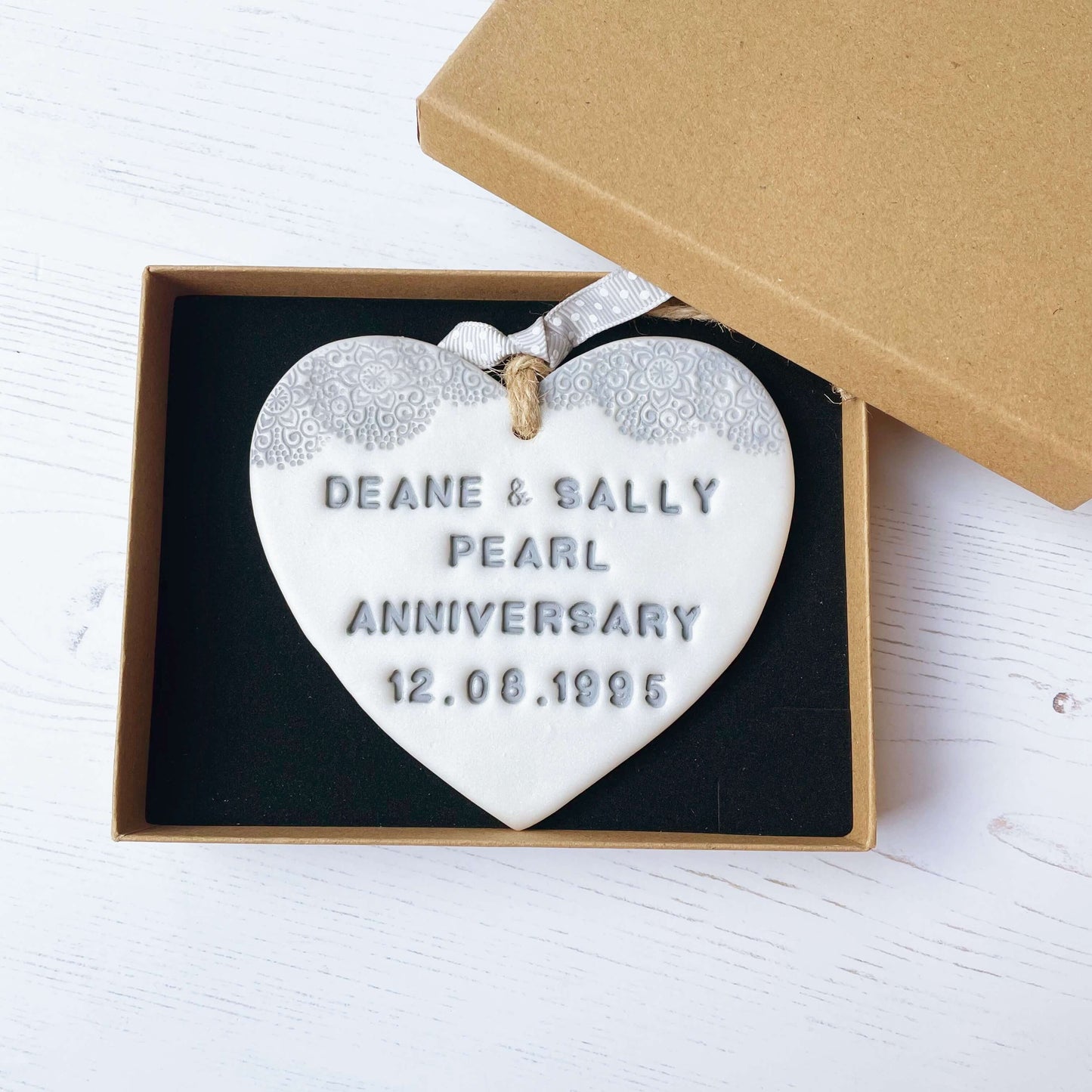 Personalised 30th Pearl anniversary gift, pearlised white clay hanging heart with a grey lace edge at the top of the heart, the heart is personalised with DEAN & SALLY PEARL ANNIVERSARY 12.08.1995