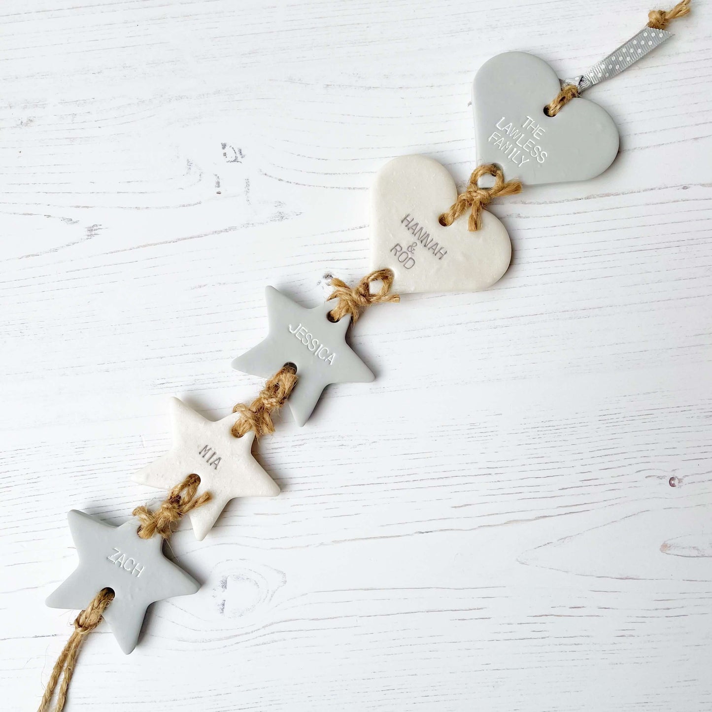 Family tree keepsake, grey small polymer clay heart with a pearlised white small heart hanging below, a small grey star hanging below, a pearlised white star hanging below and a grey star at the bottom, personalised with family names and dates