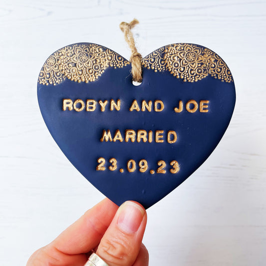 Personalised wedding gift, navy clay heart with a gold lace edge at the top of the heart with twine to hang, the heart is personalised with ROBYN AND JOE MARRIED 23.09.23