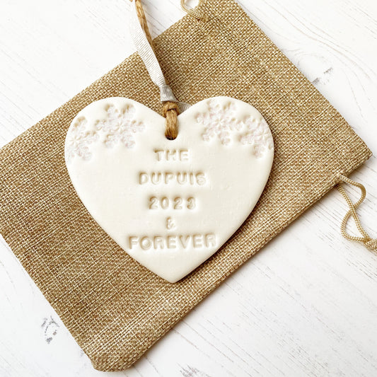 Personalised first Christmas married heart ornament, pearlised white clay with THE DUPUIS 2023 & FOREVER (text not painted), decorated with 2 iridescent glitter snowflakes on either side of the top of the heart