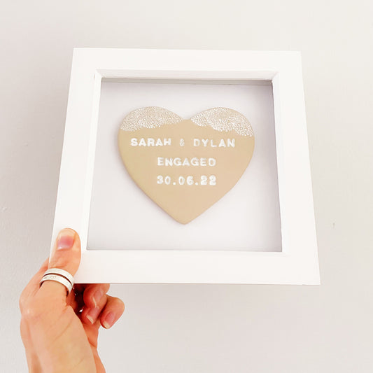 Personalised framed engagement gift, beige clay heart with a white lace edge at the top of the heart in a white box frame, the heart is personalised with SARAH & DYLAN ENGAGED 30.06.22