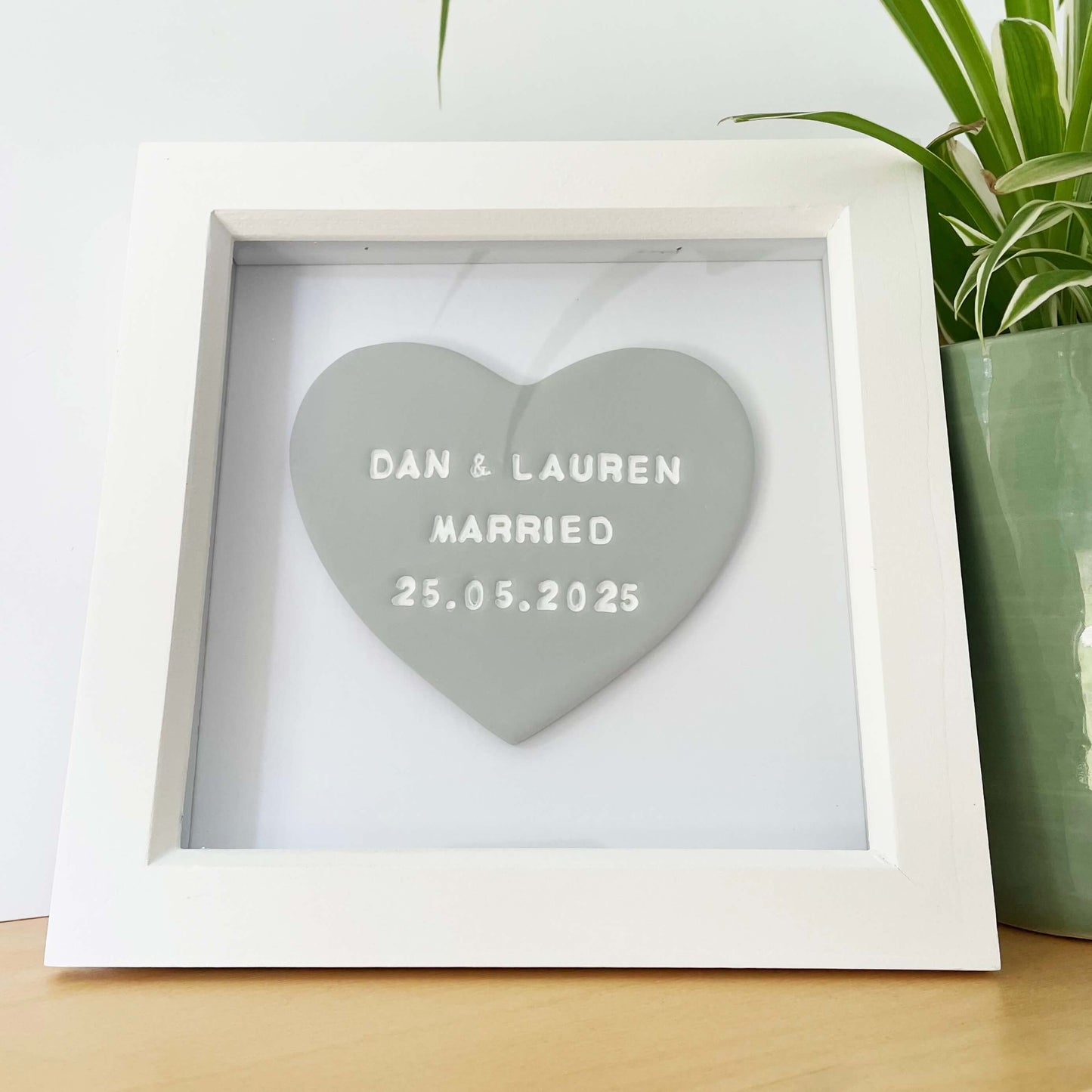 Personalised framed engagement gift, grey clay heart in a white box frame, the heart is personalised in white with DAN & LAUREN MARRIED 25.05.25
