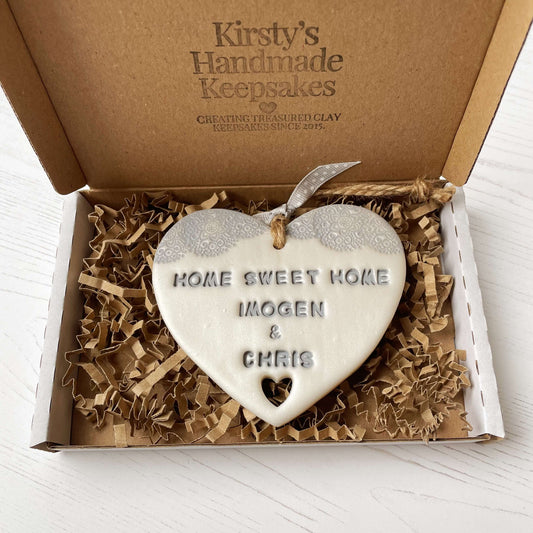 Personalised new home gift pearlised white clay heart with a grey lace edge at the top & a heart cut out at the bottom with twine for hanging personalised with HOME SWEET HOME IMOGEN & CHRIS