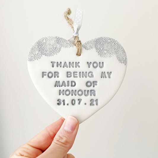 Personalised Bridesmaid thank you gift, pearlised white clay hanging heart with a grey lace edge at the top of the heart, the heart is personalised with THANK YOU FOR BEING MY MAID ОF HONOUR 31.07.21