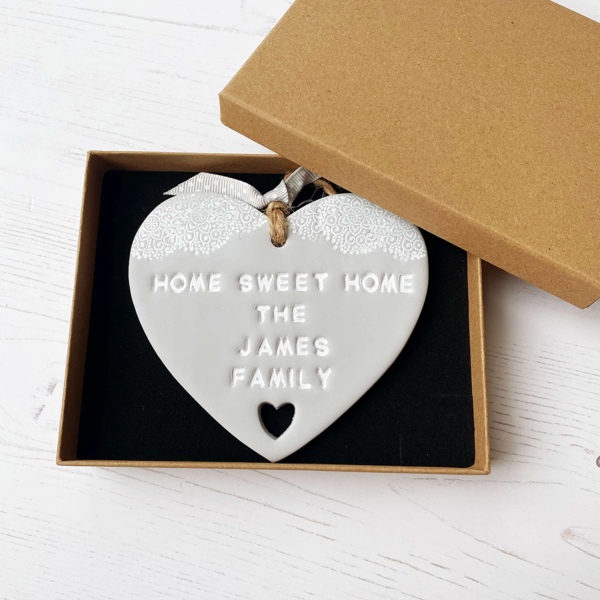 Personalised new home gift grey clay heart with a white lace edge at the top & a heart cut out at the bottom with twine for hanging personalised with HOME SWEET HOME THE JAMES FAMILY