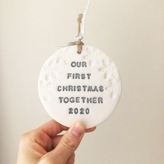 Personalised our first Christmas bauble ornament, pearlised white round clay with OUR FIRST CHRISTMAS TOGETHER 2020 in grey paint, decorated with 3 iridescent glitter snowflakes on either side of the bauble