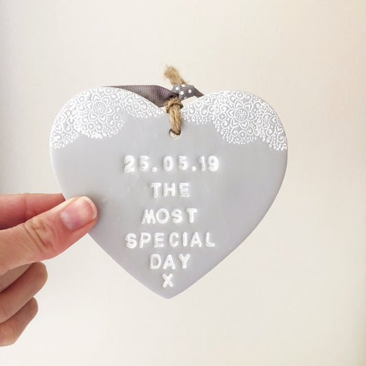 Personalised Valentine gift, grey clay heart with a white lace edge at the top of the heart with jute twine for hanging, the heart is personalised with 25.05.19 THE MOST SPECIAL DAY X