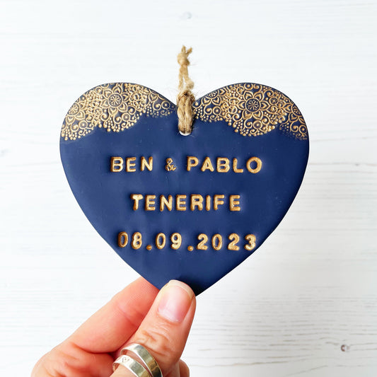 Personalised wedding gift, navy clay heart with a gold lace edge at the top of the heart with twine to hang, the heart is personalised with BEN & PABLO TENERIFE 08.09.2023
