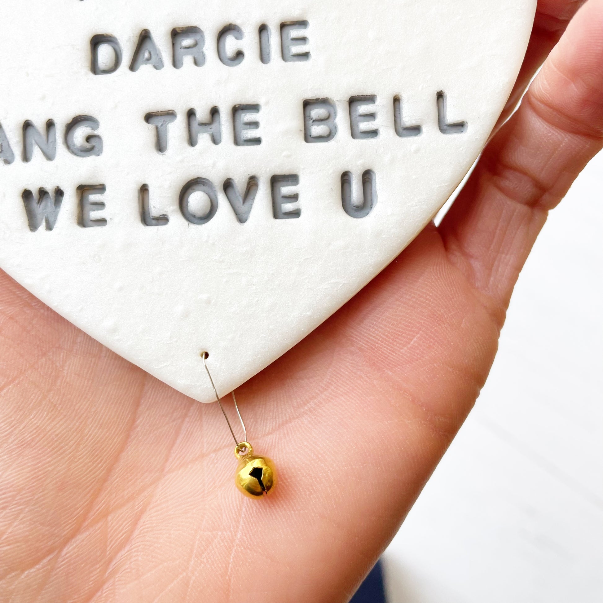 Personalised cancer survivor gift, pearlised white clay hanging heart with a grey lace edge at the top of the heart and a gold bell hanging below, the heart is personalised with 10-01-24 DARCIE RANG THE BELL WE LOVE U