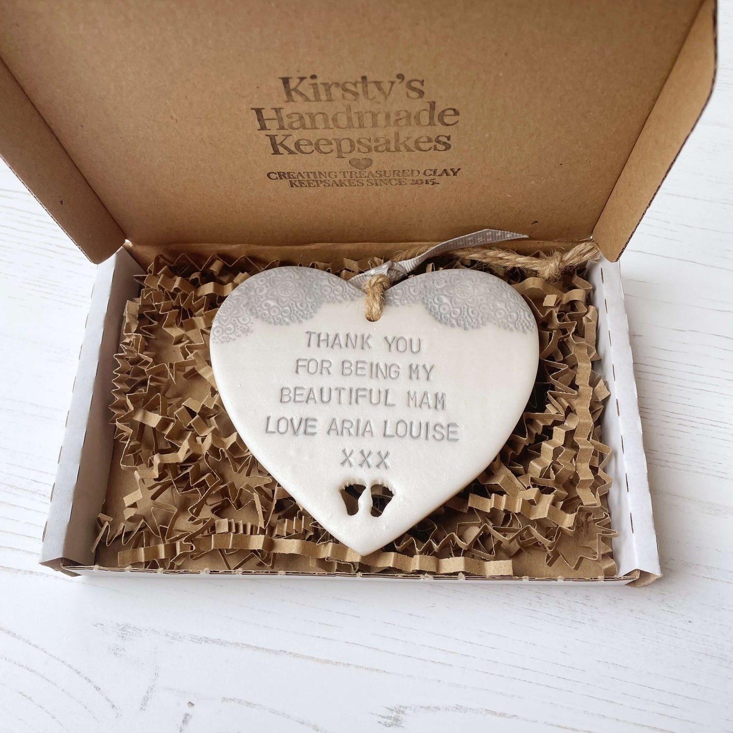 Personalised Mother’s Day gift, pearlised white clay hanging heart with baby feet cut out at the bottom of the heart and a grey lace edge at the top of the heart, the heart is personalised with THANK YOU FOR BEING MY BEAUTIFUL MAM LOVE ARIA LOUISE XXX