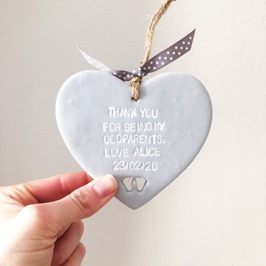 Personalised Godparent gift, grey clay hanging heart with baby feet cut out of the bottom, the heart is personalised with THANK YOU FOR BEING MY FOR BEING MY GODPARENTS. LOVE ALICE 23/02/20