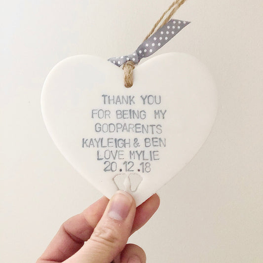 Personalised Godparents gift, pearlised white clay hanging heart with baby feet cut out of the bottom, the heart is personalised with THANK YOU FOR BEING MY GODPARENTS KAYLEIGH & BEN LOVE MYLIE 20.12.18