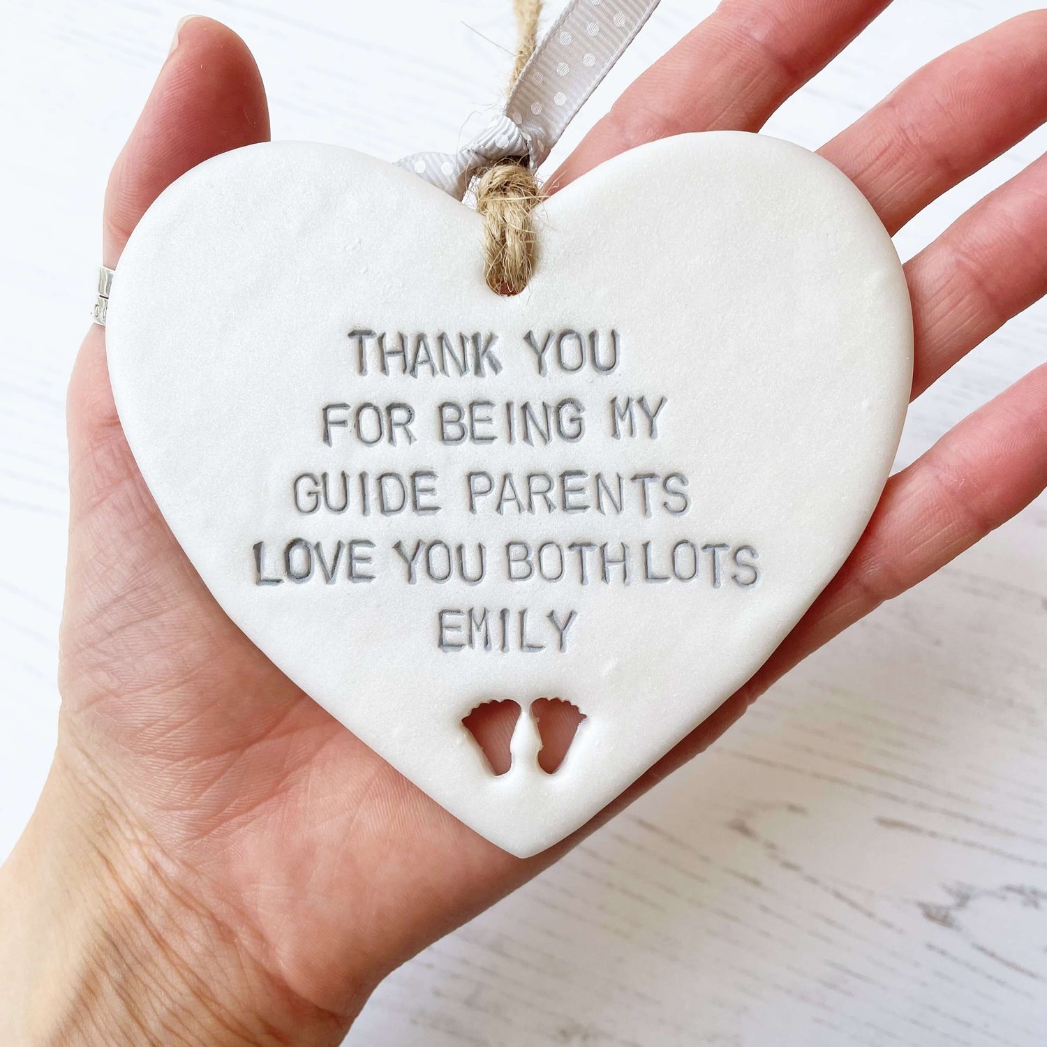 Personalised guide parents gift, pearlised white clay hanging heart with baby feet cut out of the bottom, the heart is personalised with THANK YOU FOR BEING MY GUIDE PARENTS LOVE YOU BITH LOTS EMILY