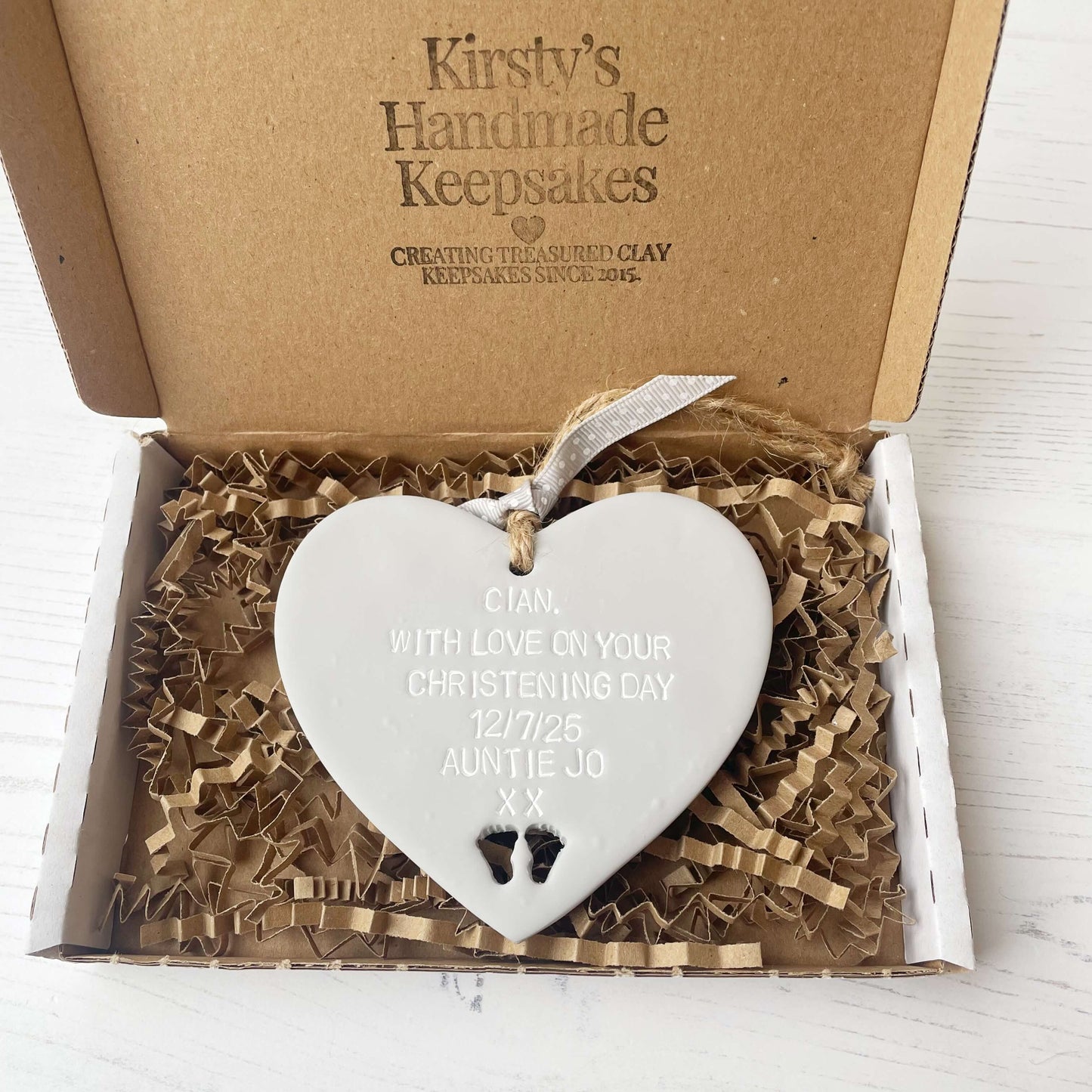 Personalised Christening baptism gift, grey clay hanging heart, with baby feet cut out of the bottom, the heart is personalised with CIAN, WITH LOVE ON YOUR CHRISTENING DAY 12/7/25 AUNTIE JO XX