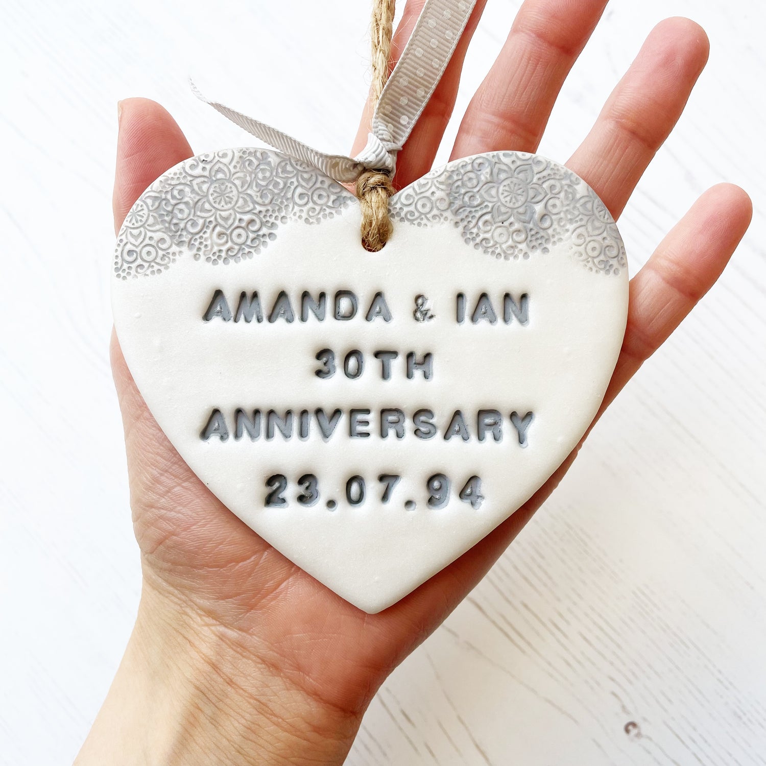 Personalised 30th Pearl anniversary gift, pearlised white clay hanging heart with a grey lace edge at the top of the heart, the heart is personalised with AMANDA & IAN 30TH ANNIVERSARY 23.07.94