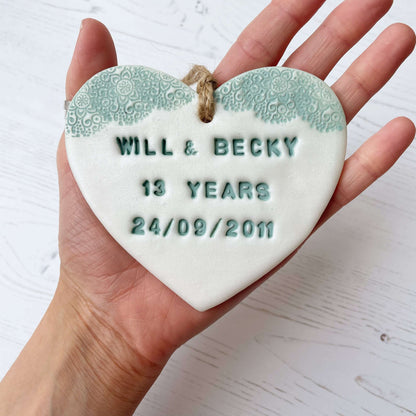 Personalised 13th anniversary gift, pearlised white clay hanging heart with a safe green lace edge at the top of the heart, the heart is personalised with WILL & BECKY 13 YEARS 24/09/2011