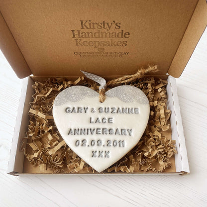 Personalised 13th anniversary gift, pearlised white clay hanging heart with a grey lace edge at the top of the heart, the heart is personalised with GARY & SUZANNE LACE ANNIVERSARY 02.09.2011 XXX