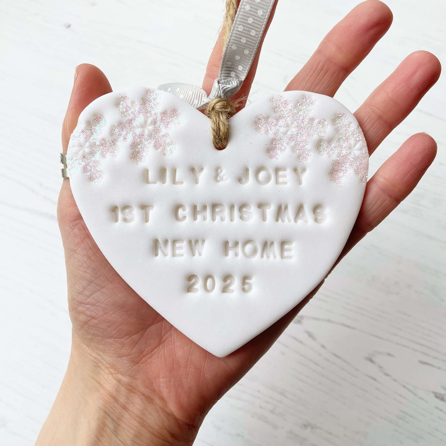 Personalised first Christmas new home heart ornament, glitter white clay with LILY & JOEY 1ST CHRISTMAS NEW HOME 2025 (text not painted), decorated with 2 iridescent glitter snowflakes on either side of the top of the heart