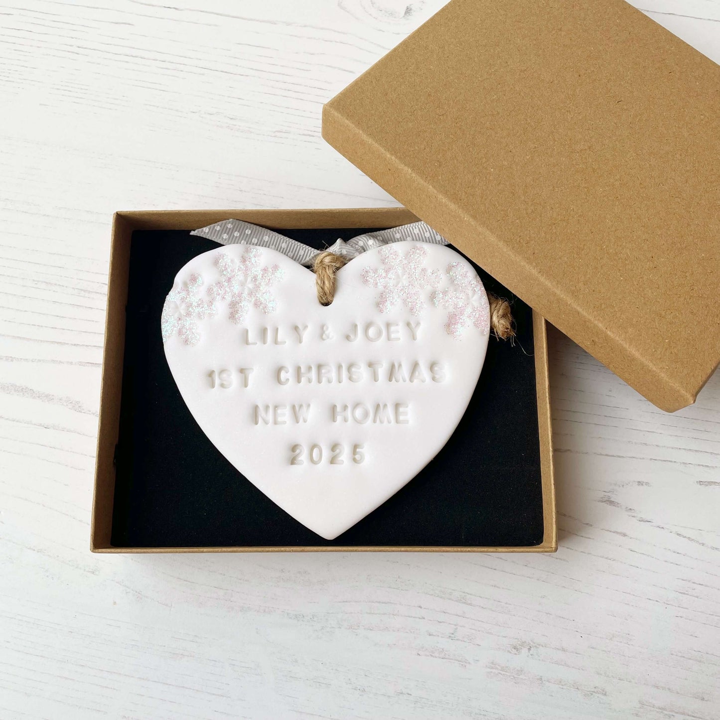 Personalised first Christmas new home heart ornament, glitter white clay with LILY & JOEY 1ST CHRISTMAS NEW HOME 2025 (text not painted), decorated with 2 iridescent glitter snowflakes on either side of the top of the heart