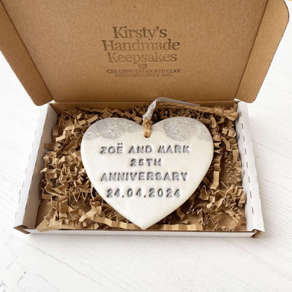 Personalised 25th anniversary gift, pearlised white clay hanging heart with a grey lace edge at the top of the heart, the heart is personalised with ZOË AND MARK 25TH ANNIVERSARY 24.04.2024