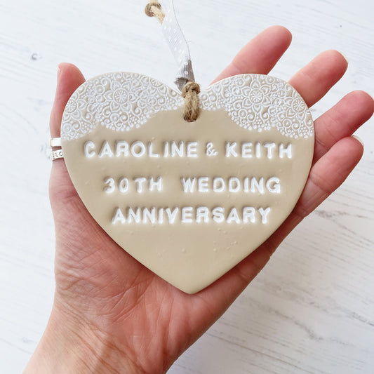 Personalised anniversary gift, beige clay heart with a white lace edge at the top of the heart with jute twine for hanging, the heart is personalised with CAROLINE & KEITH 30TH WEDDING ANNIVERSARY 