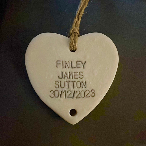 A pearlised white polymer clay heart add on for the Grandparent keepsake with a hanging twine loop, featuring personalised engraved text reading 'FINLEY JAMES SUTTON 30/12/2023' on a dark background.