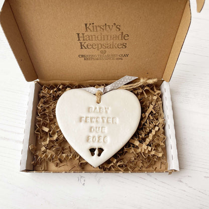 Personalised baby reveal gift, pearlised white clay heart with feet cut out of the bottom personalised with BABY FEWSTER DUE 2026