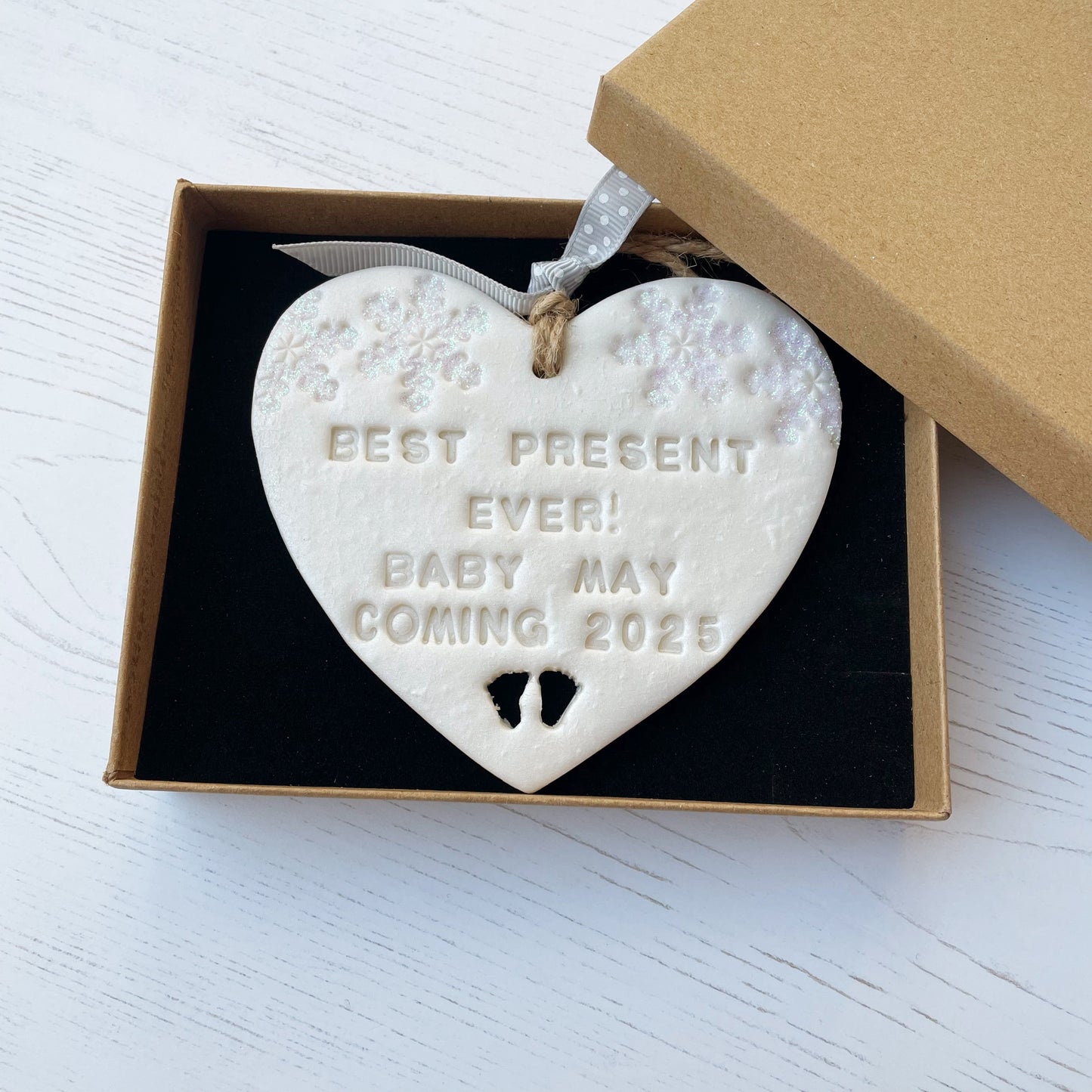 Personalised baby reveal Christmas heart ornament, pearlised white clay with BEST PRESENT EVER! BABY MAY COMING 2025, decorated with 2 iridescent glitter snowflakes on either side of the top of the heart