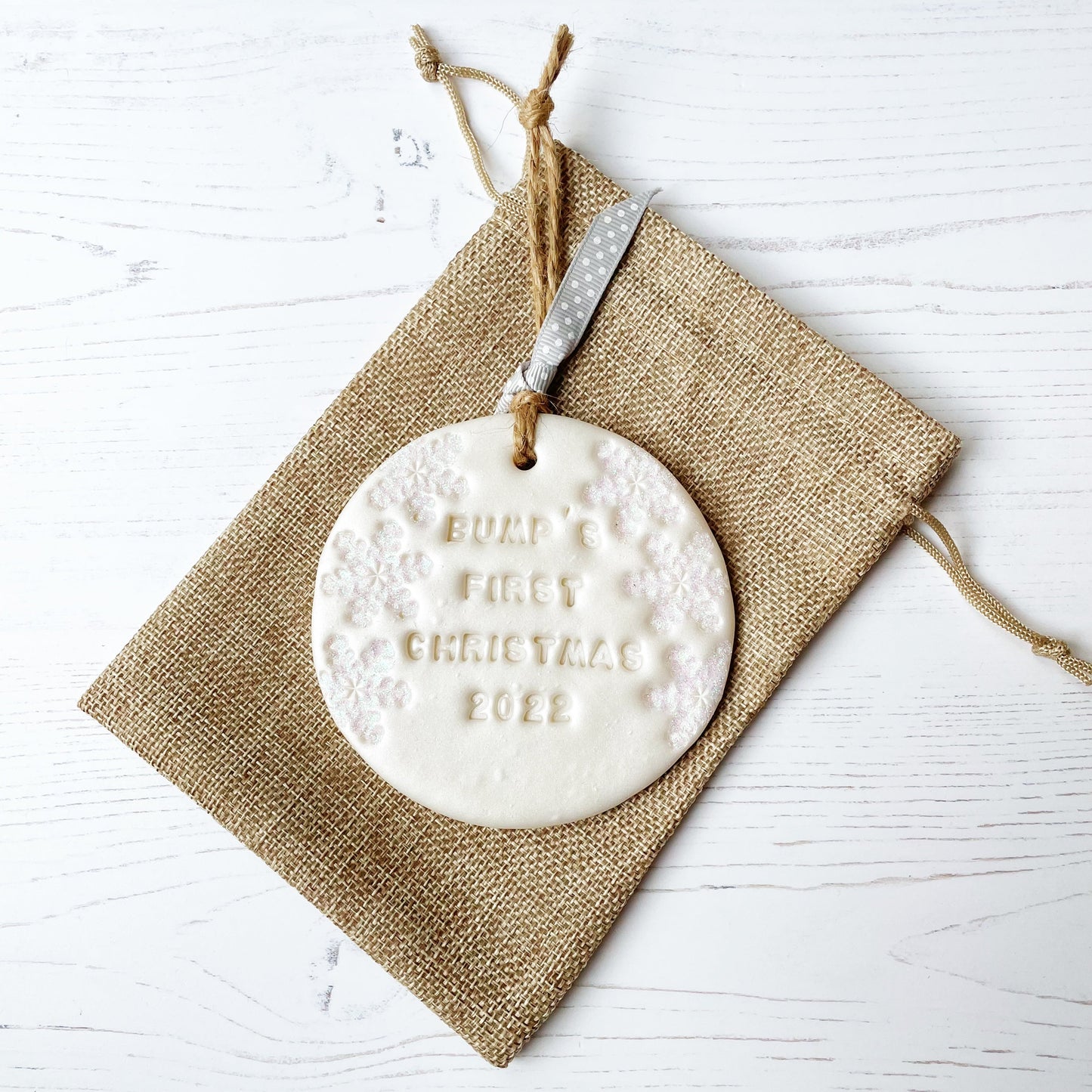 Personalised bump's first Christmas bauble ornament, pearlised white round clay with BUMP’S FIRST CHRISTMAS 2022 (text not painted), decorated with 3 iridescent glitter snowflakes on either side of the bauble